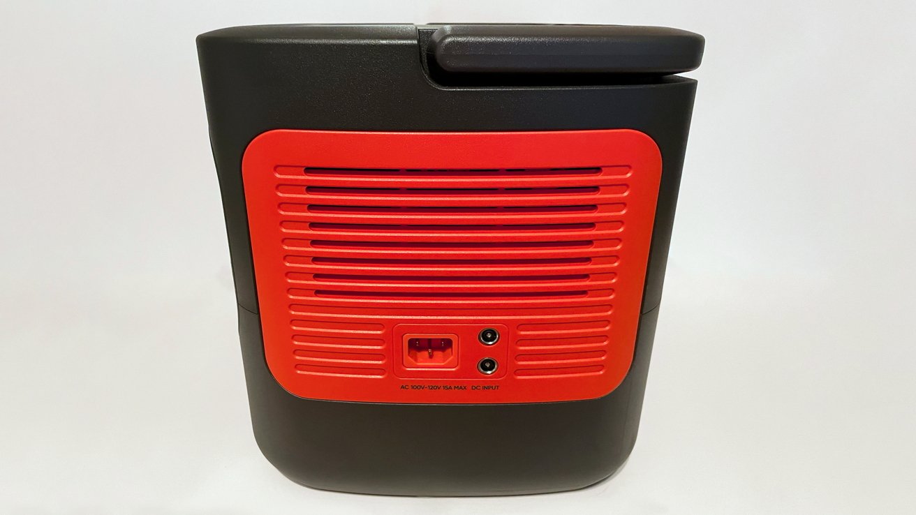 Black device with a red vented panel featuring power plugs and input sockets, against a plain background.