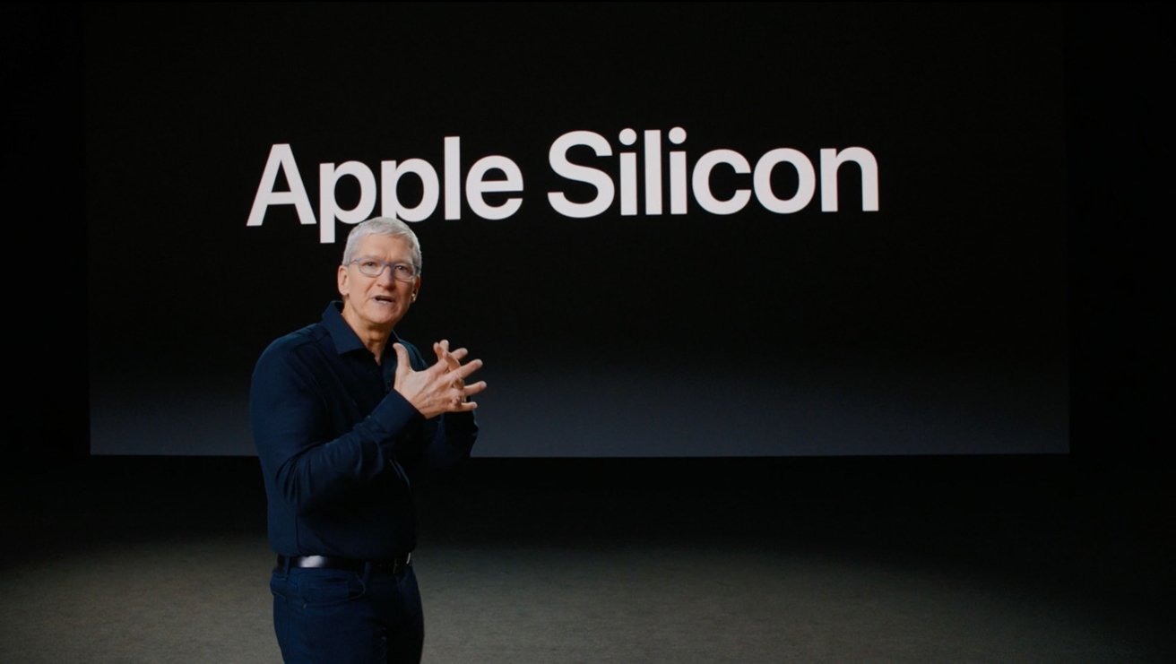 Person presenting on stage with the words Apple Silicon displayed on a large screen behind them.